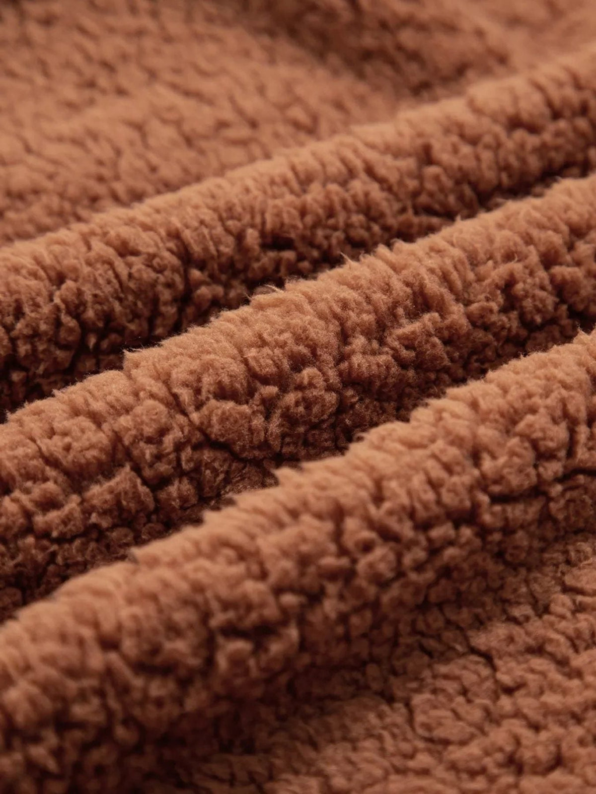 Close-up of plush teddy texture on women's brown zip-up jacket